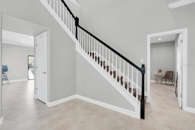 staircase with a towering ceiling and tile patterned flooring