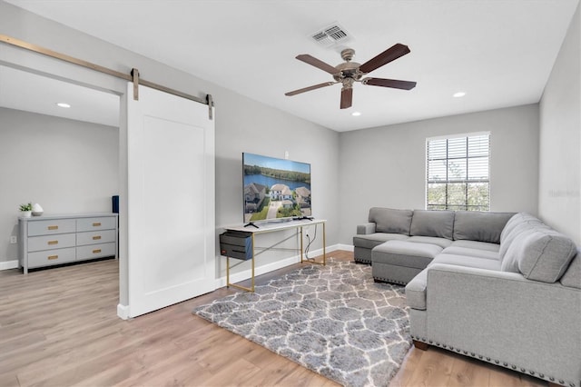 living room with hardwood / wood-style floors, a barn door, and ceiling fan