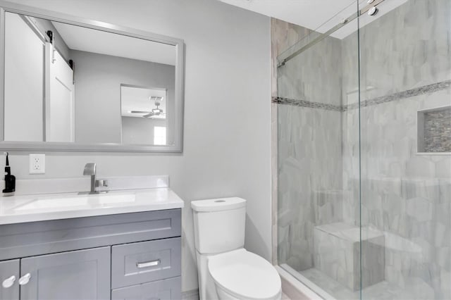 bathroom with vanity, a shower with shower door, toilet, and ceiling fan