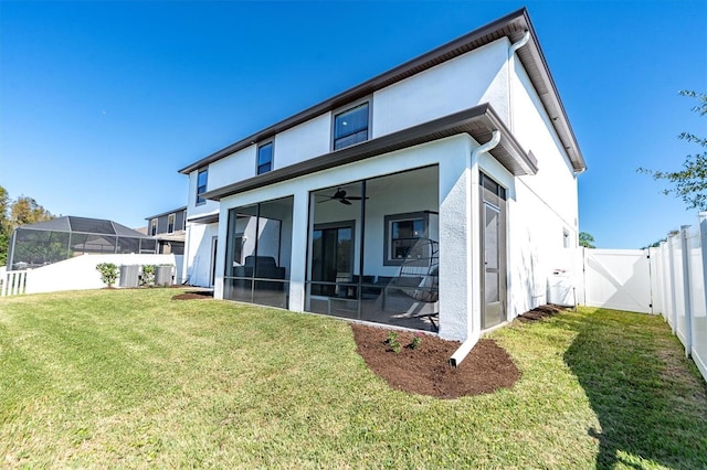 back of house featuring a sunroom, a lawn, central AC, glass enclosure, and ceiling fan