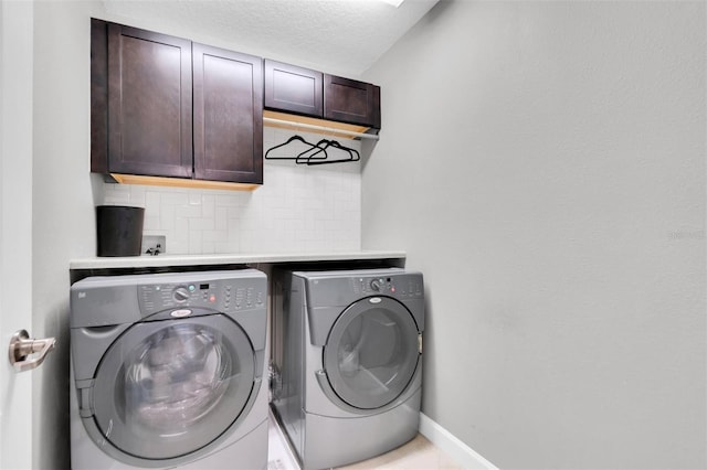 laundry area with cabinets, a textured ceiling, and separate washer and dryer