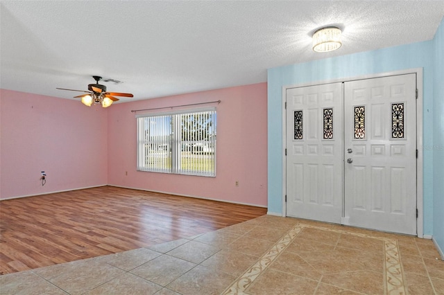 foyer with ceiling fan, a textured ceiling, and light wood-type flooring