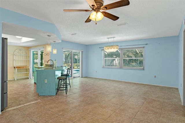 kitchen featuring ceiling fan, a textured ceiling, decorative light fixtures, and a kitchen bar