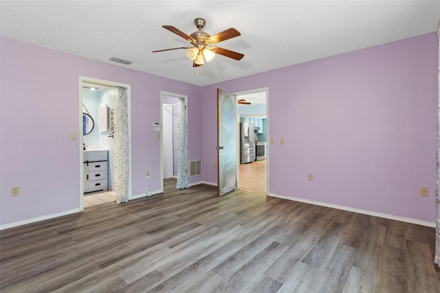 unfurnished bedroom featuring light hardwood / wood-style floors, stainless steel fridge, ensuite bathroom, and ceiling fan