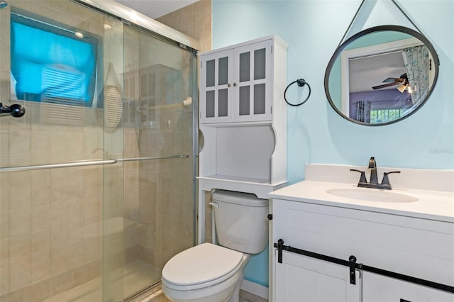 bathroom with toilet, vanity, and a shower with door