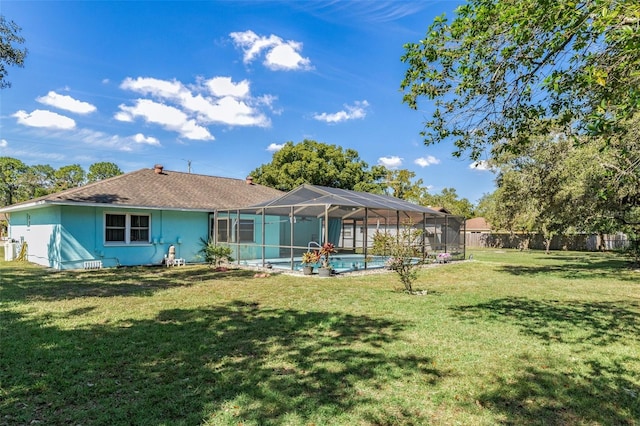 back of property with a fenced in pool, a lawn, and glass enclosure