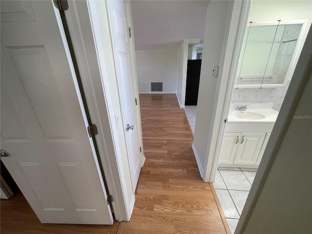 corridor with sink and light wood-type flooring