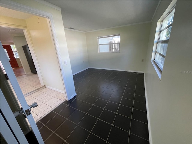 unfurnished room with dark tile patterned flooring, crown molding, and a wealth of natural light