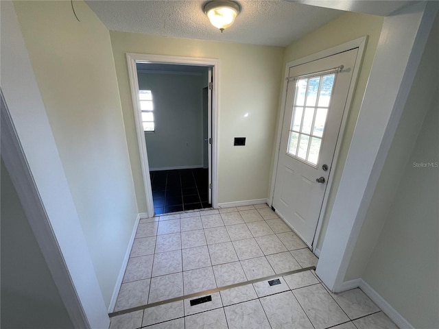 doorway to outside with a textured ceiling and light tile patterned floors