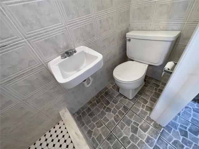 bathroom with tile walls, sink, and toilet