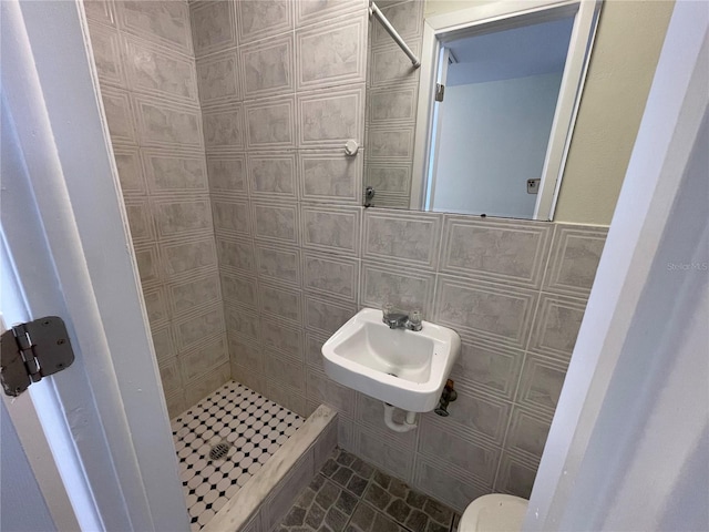 bathroom featuring a shower, tile walls, sink, and toilet