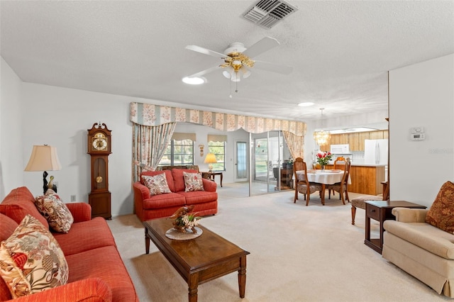 living room with light colored carpet, a textured ceiling, and ceiling fan with notable chandelier