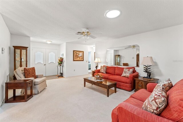 carpeted living room featuring french doors, ceiling fan, and a textured ceiling