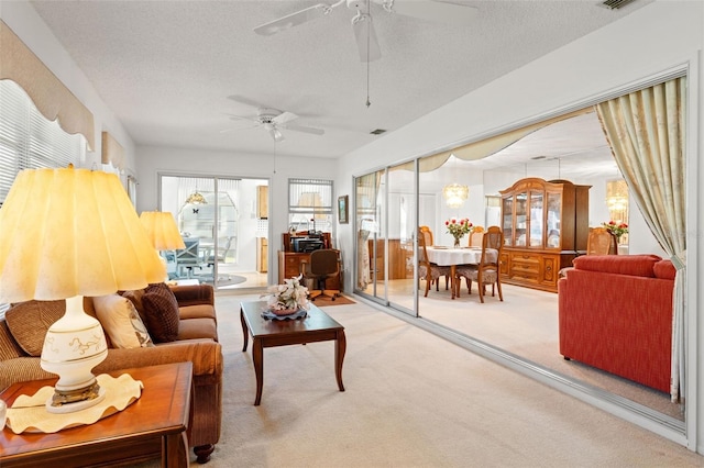 carpeted living room featuring ceiling fan and a textured ceiling