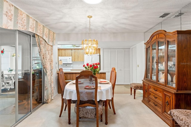 carpeted dining area with an inviting chandelier and a textured ceiling