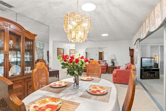 dining room featuring light carpet, a notable chandelier, and a textured ceiling