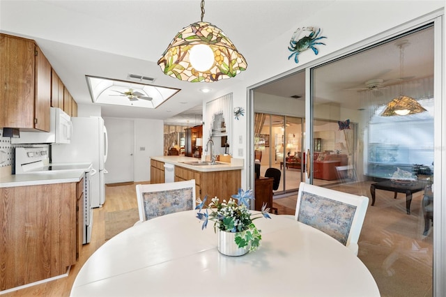 dining space featuring sink, light hardwood / wood-style flooring, a skylight, and ceiling fan