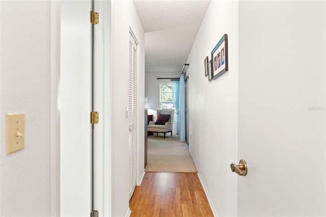 corridor with a textured ceiling and light wood-type flooring