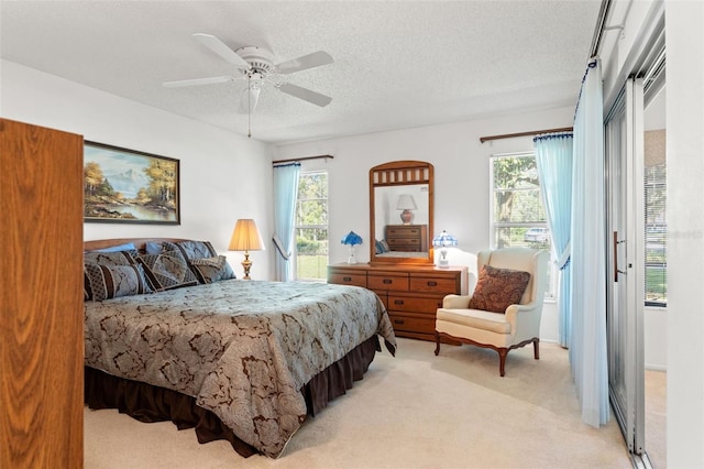 bedroom with multiple windows, a textured ceiling, light colored carpet, and ceiling fan