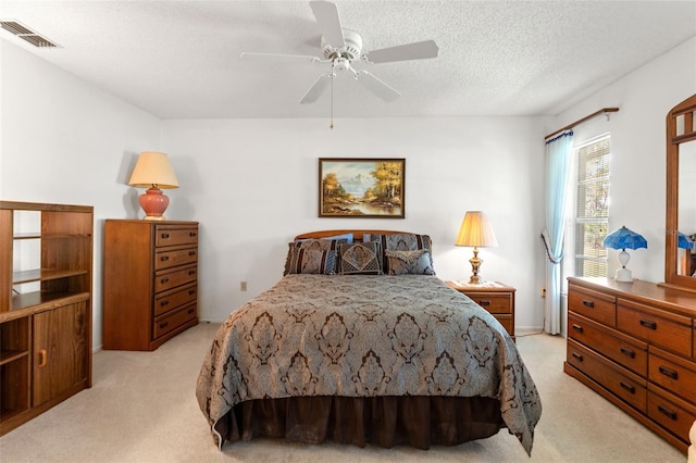 carpeted bedroom with ceiling fan and a textured ceiling