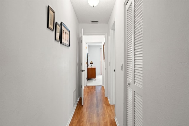 hall with wood-type flooring and a textured ceiling