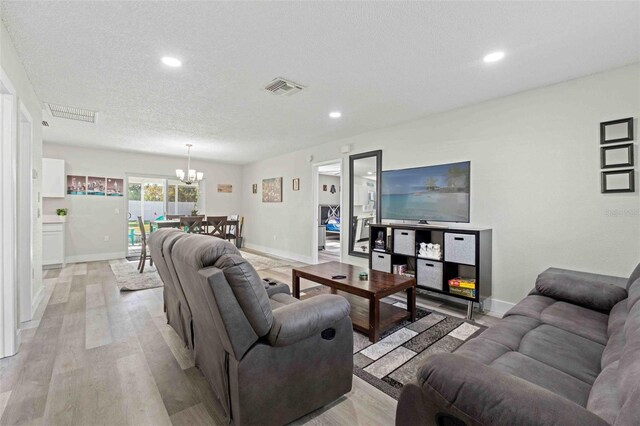 living room with a textured ceiling, light hardwood / wood-style flooring, and an inviting chandelier