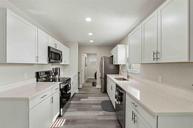 kitchen featuring appliances with stainless steel finishes, light hardwood / wood-style flooring, white cabinets, and sink