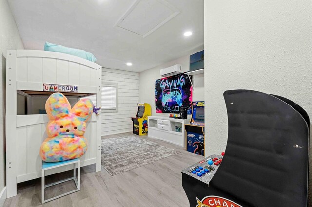 game room with a wall mounted air conditioner and hardwood / wood-style flooring