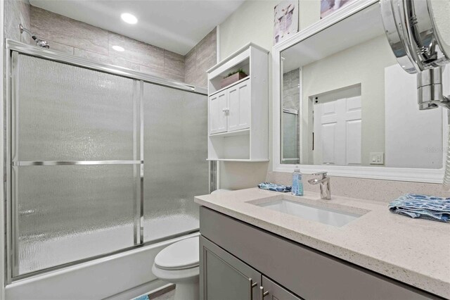 full bathroom featuring toilet, enclosed tub / shower combo, and vanity