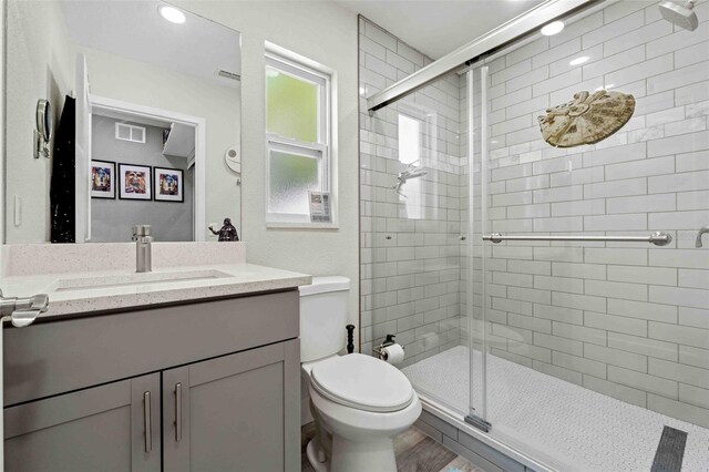 bathroom with vanity, hardwood / wood-style floors, a shower with shower door, and toilet