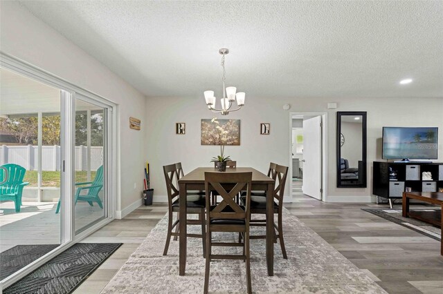 dining area with a notable chandelier, a textured ceiling, and wood-type flooring