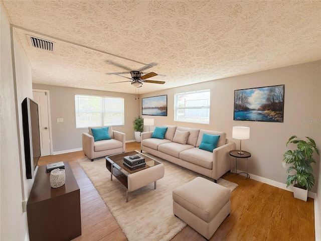 living room with ceiling fan, a textured ceiling, and light hardwood / wood-style floors