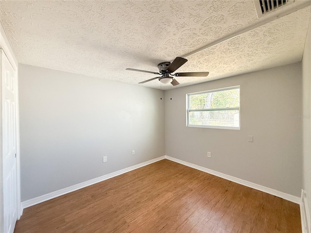 unfurnished room featuring hardwood / wood-style floors, ceiling fan, and a textured ceiling