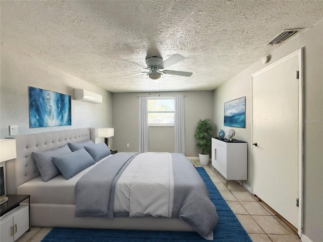 bedroom with ceiling fan, a textured ceiling, light tile patterned floors, and a wall mounted air conditioner