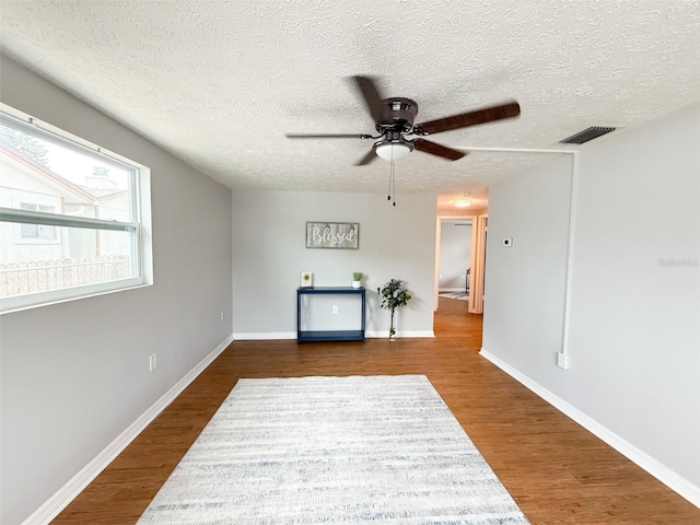 living room featuring a textured ceiling, a ceiling fan, dark wood-style flooring, and baseboards
