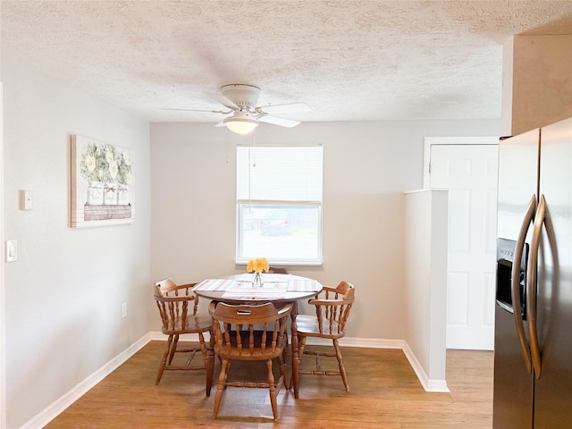 dining room with light wood-type flooring, baseboards, ceiling fan, and a textured ceiling
