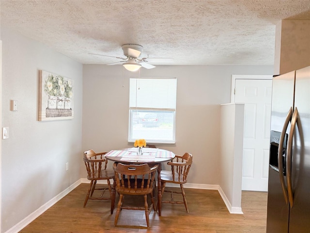 dining area with wood finished floors, ceiling fan, baseboards, and a textured ceiling