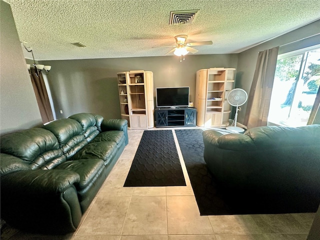 tiled living area with a ceiling fan, a textured ceiling, and visible vents