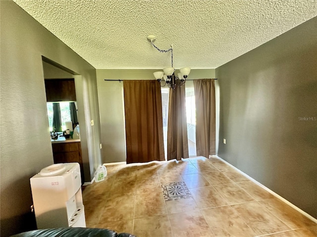 unfurnished dining area with an inviting chandelier, a textured ceiling, and tile patterned floors