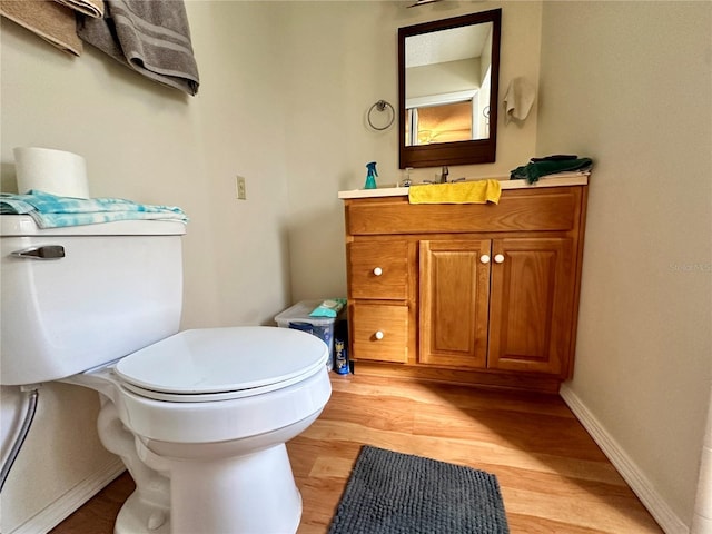 bathroom featuring toilet, wood finished floors, and vanity