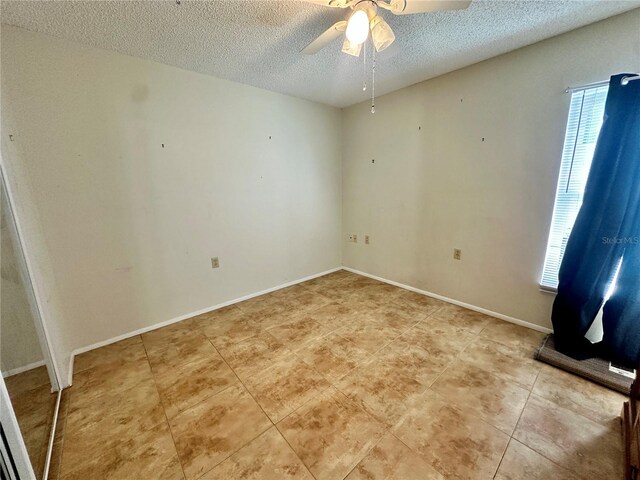 spare room with baseboards, a ceiling fan, a textured ceiling, and light tile patterned floors