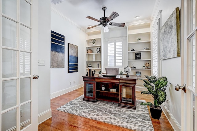 office featuring ceiling fan, ornamental molding, built in shelves, and hardwood / wood-style floors