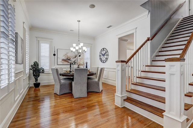 dining room featuring a notable chandelier, ornamental molding, and light wood-type flooring