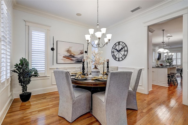 dining area with crown molding, a notable chandelier, and light hardwood / wood-style floors