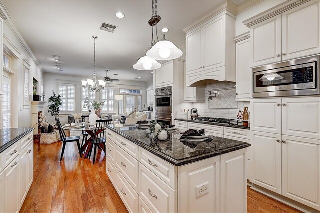 kitchen featuring hanging light fixtures, light hardwood / wood-style floors, appliances with stainless steel finishes, and a kitchen island