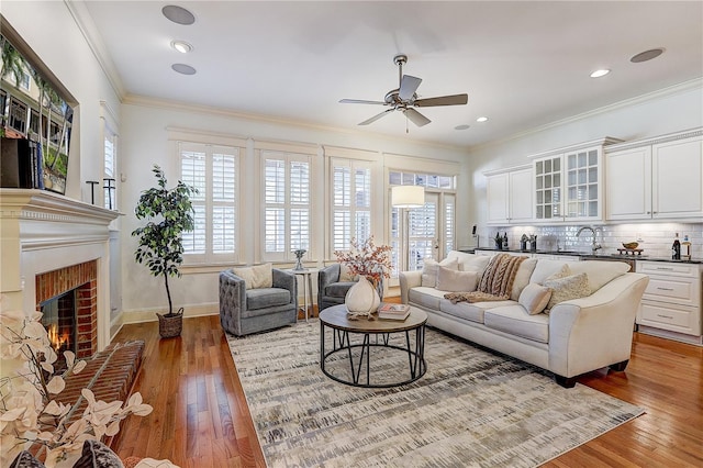 living room with sink, a brick fireplace, crown molding, and a healthy amount of sunlight