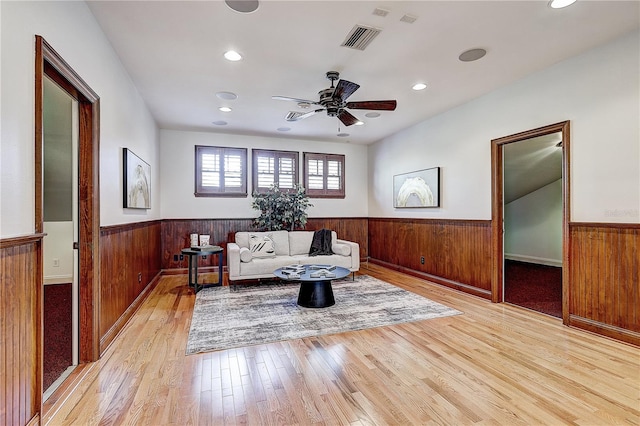 sitting room featuring light hardwood / wood-style flooring, ceiling fan, and wood walls