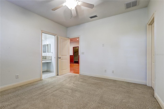 unfurnished bedroom featuring ceiling fan, light carpet, and ensuite bathroom