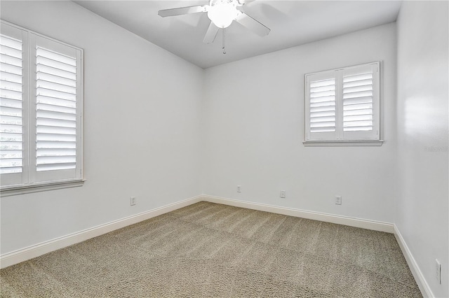 carpeted spare room featuring ceiling fan and a wealth of natural light