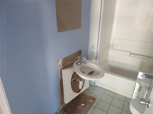 bathroom with toilet, sink, and tile patterned floors